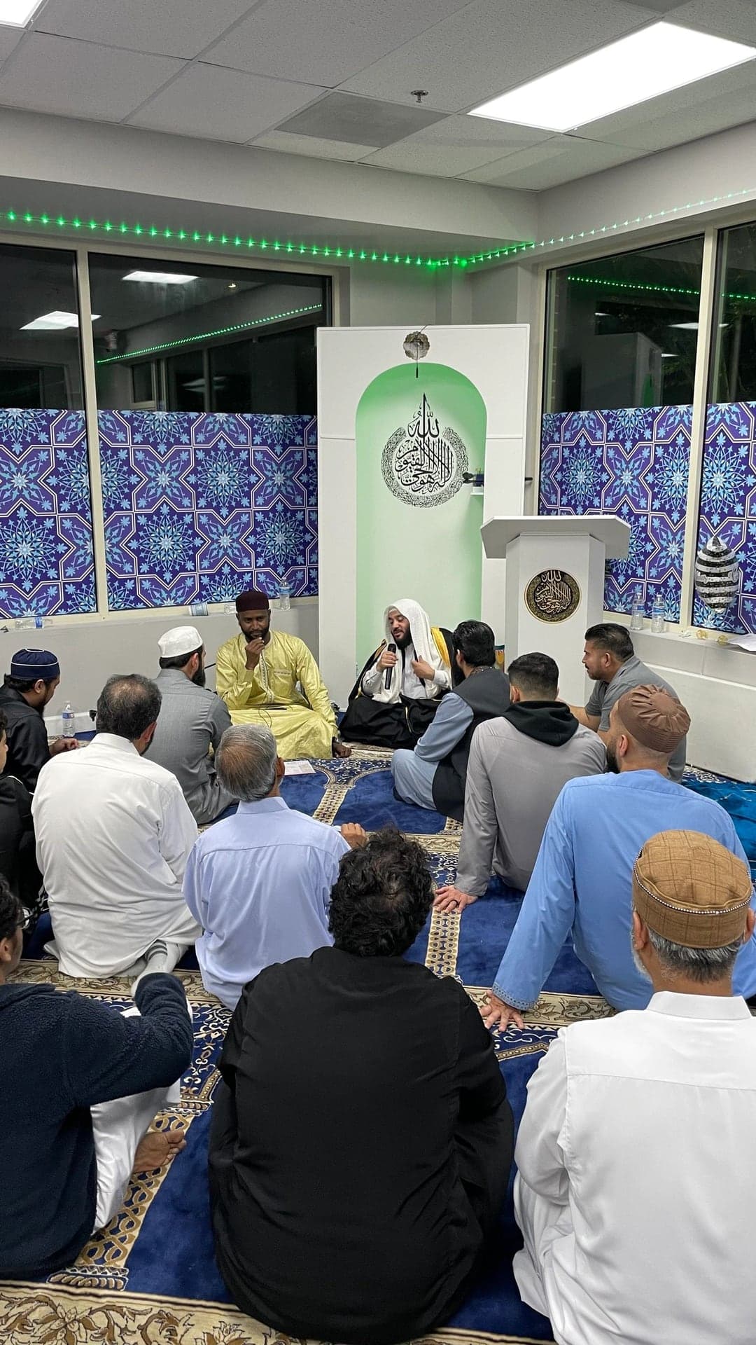 Brothers gathered on the prayer hall carpet for a talk at AQSA Center