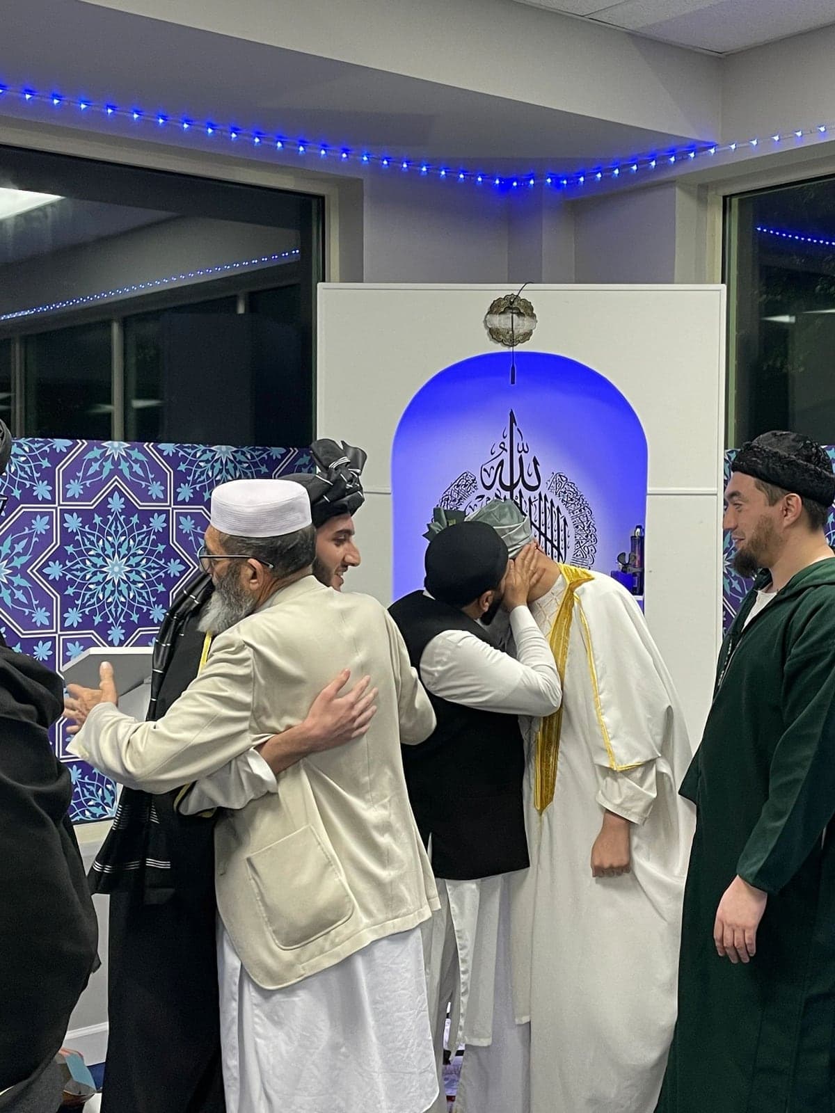 Community members embracing a young graduate in celebration at AQSA Center