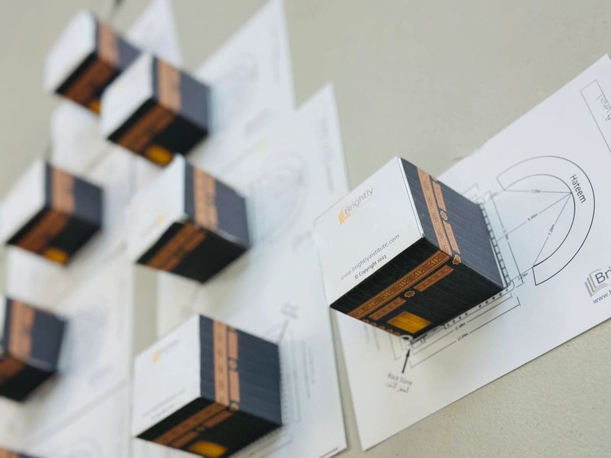 Paper Kaaba models made by students displayed on their templates