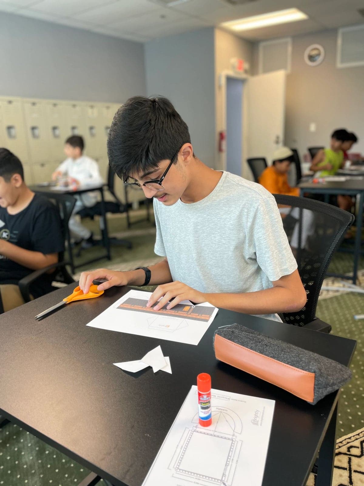 A student carefully folding a Kaaba model during a youth workshop
